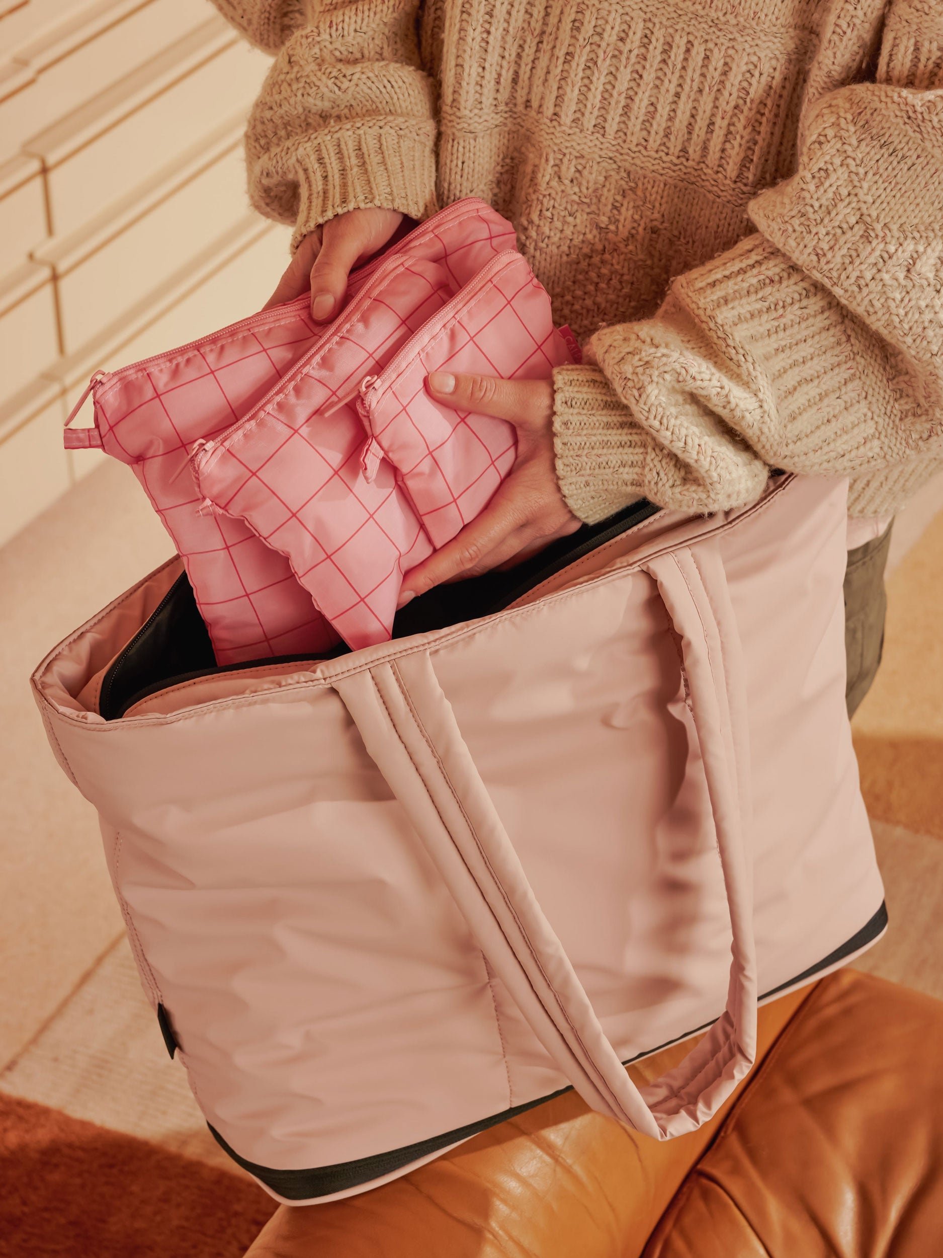 Model packing CALPAK Compakt zippered pouch set in duffel bag in pink grid
