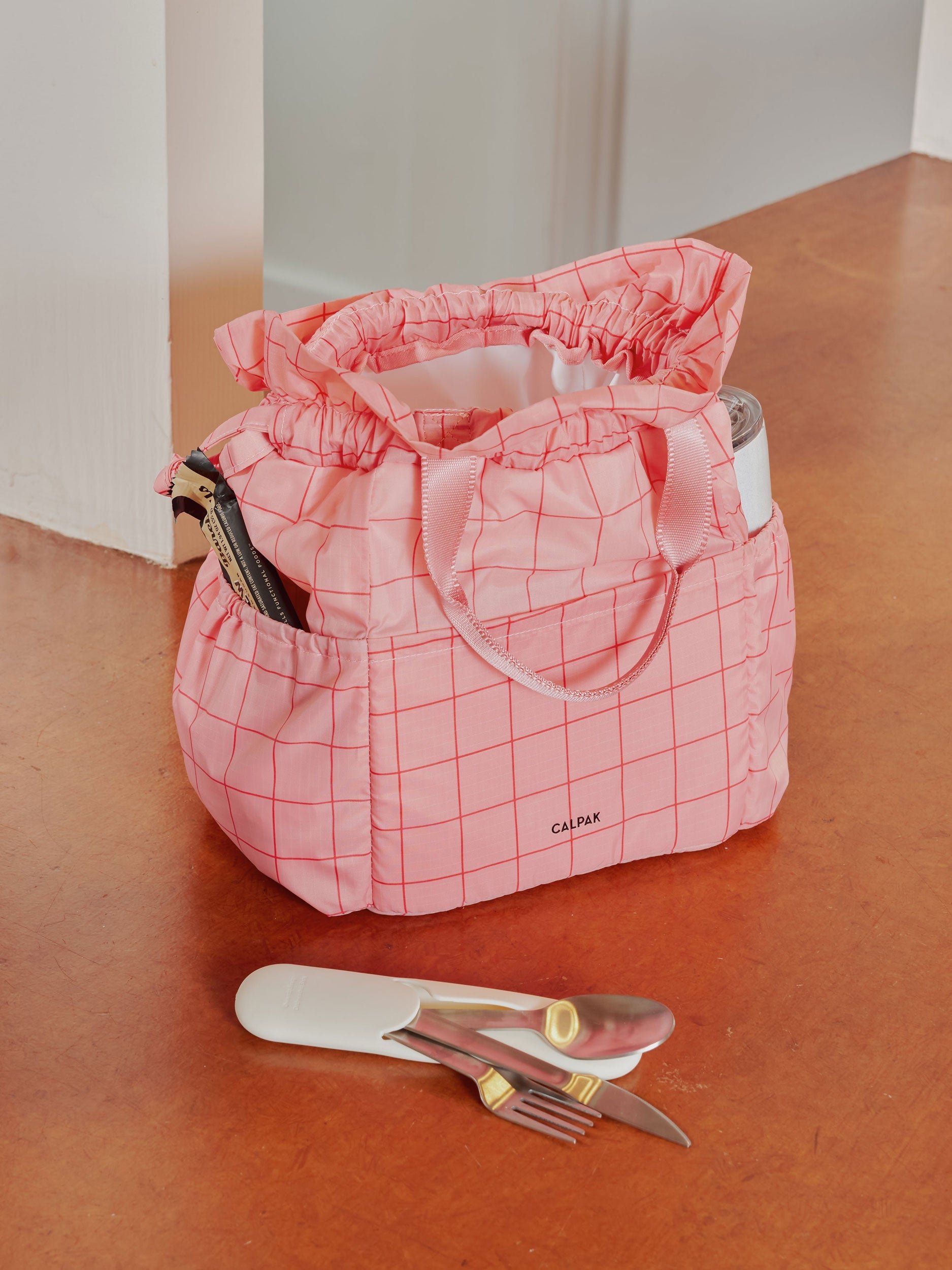 CALPAK Insulated Lunch Bag with dual top handles and side pockets in pink grid print