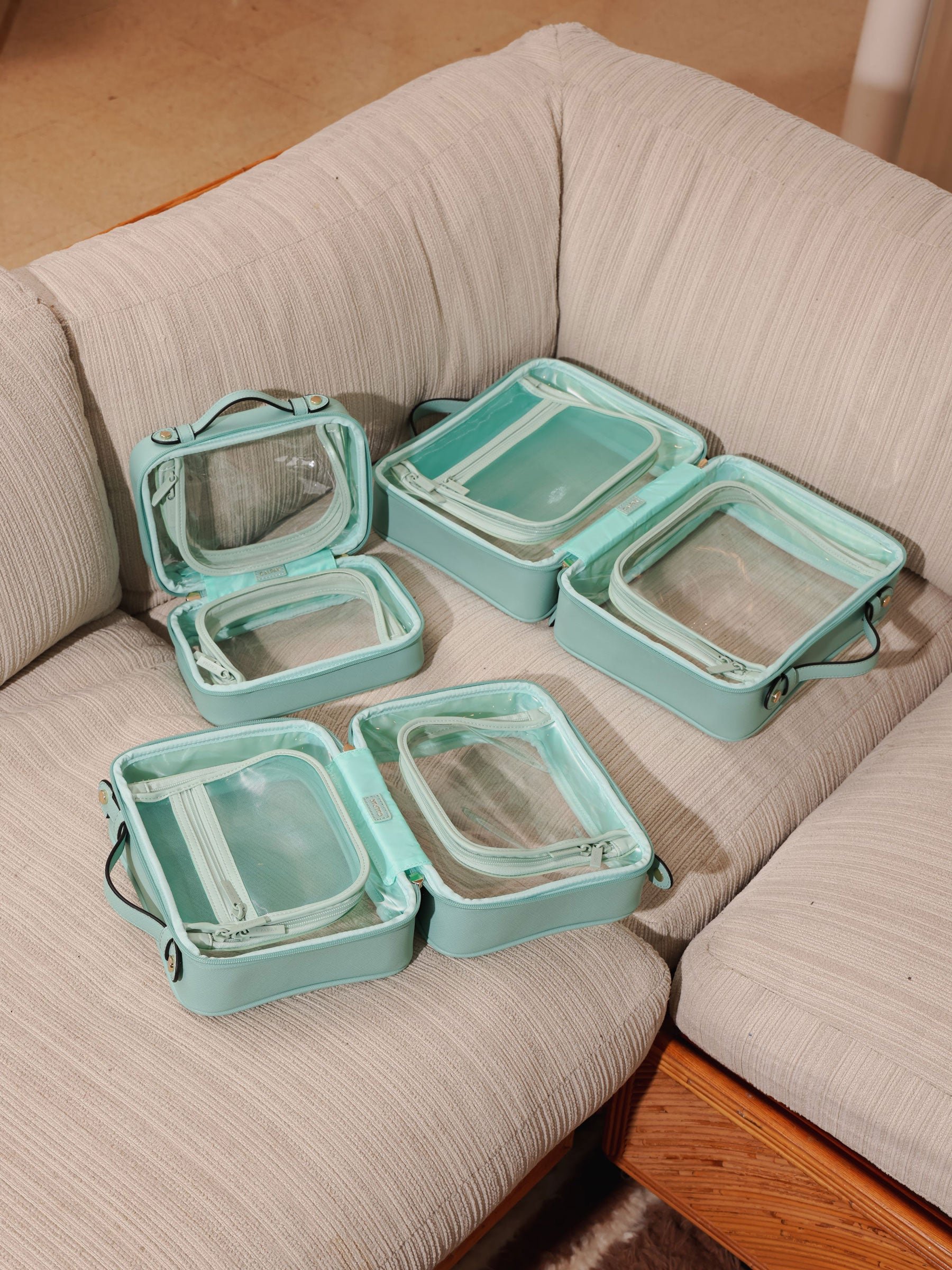 CALPAK aqua clear makeup cases with zippered compartments in small, medium and large sizes