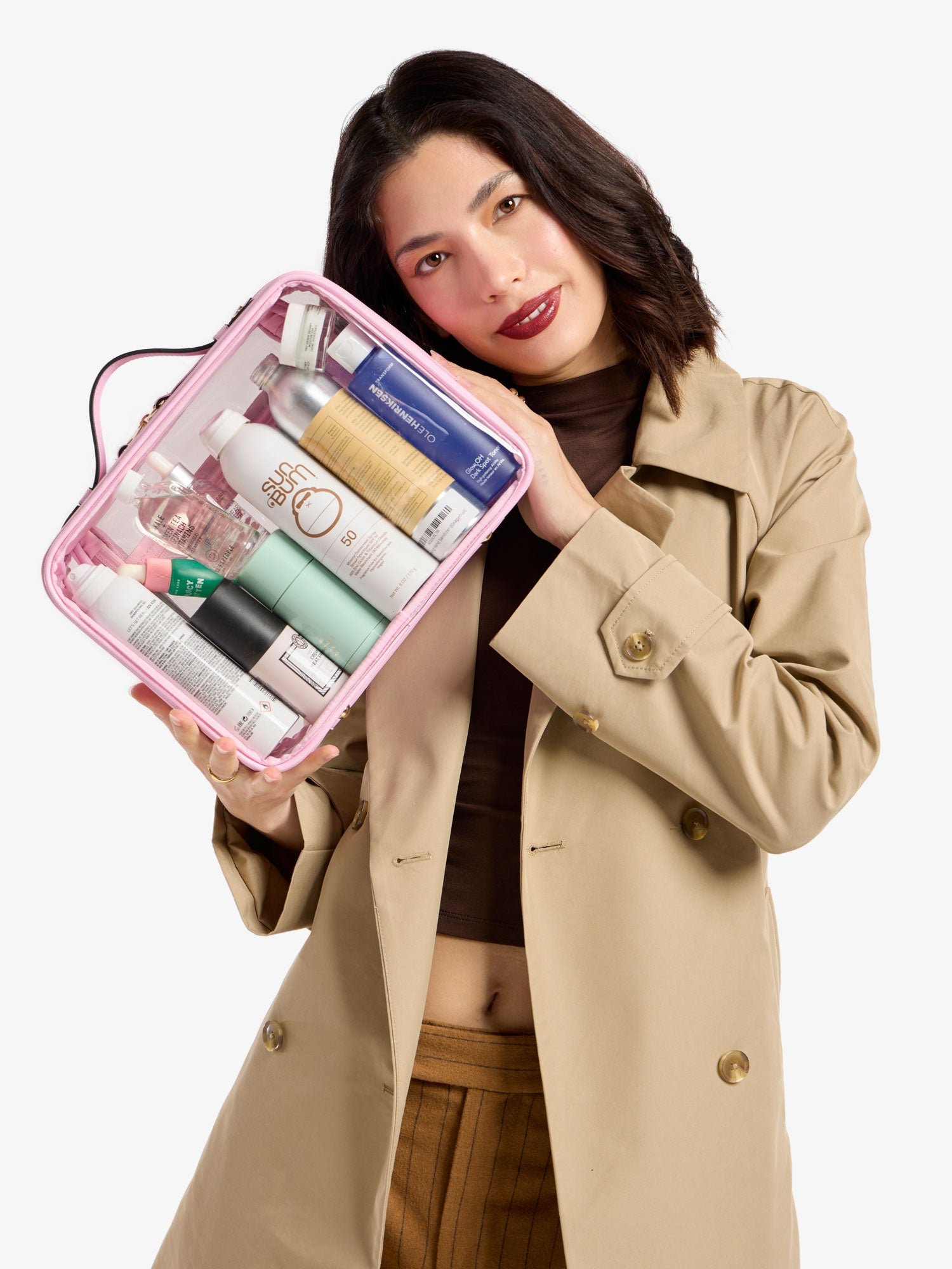 Model holding CALPAK large clear cosmetic case in strawberry pink