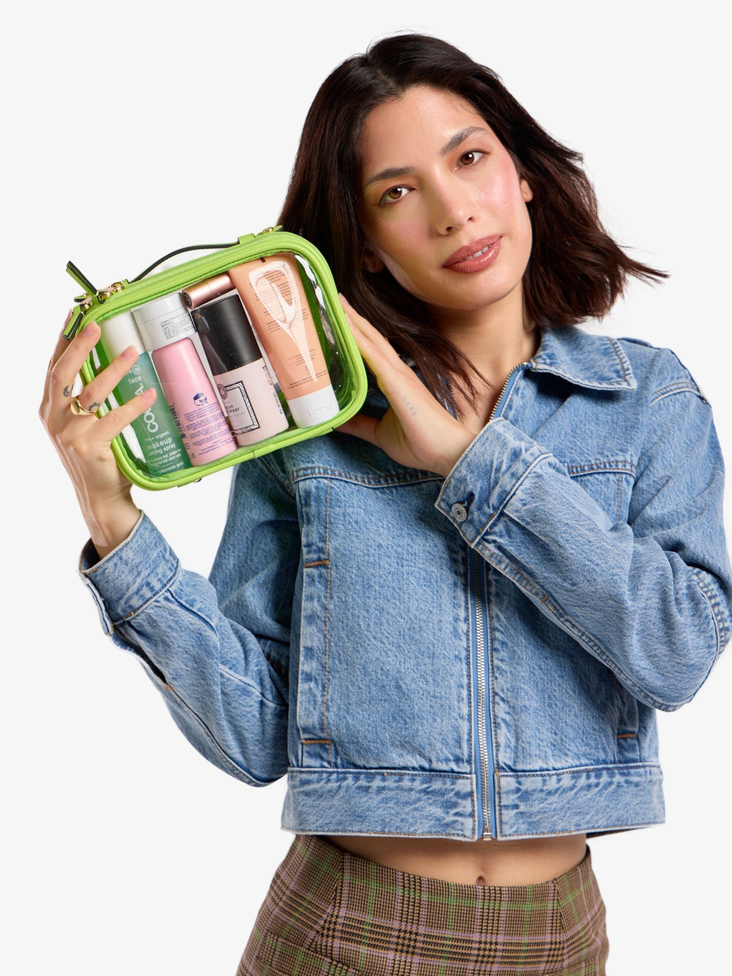 Model holding up CALPAK small clear cosmetic case in bright green
