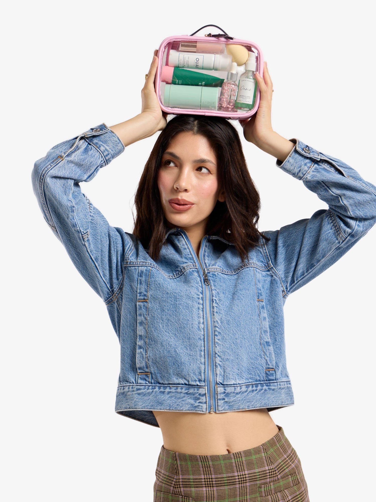 Model holding CALPAK small clear cosmetic case above head in pink