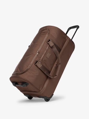Side view of dark brown large travel duffel bag with wheels and top handle extended; DRL2301-WALNUT