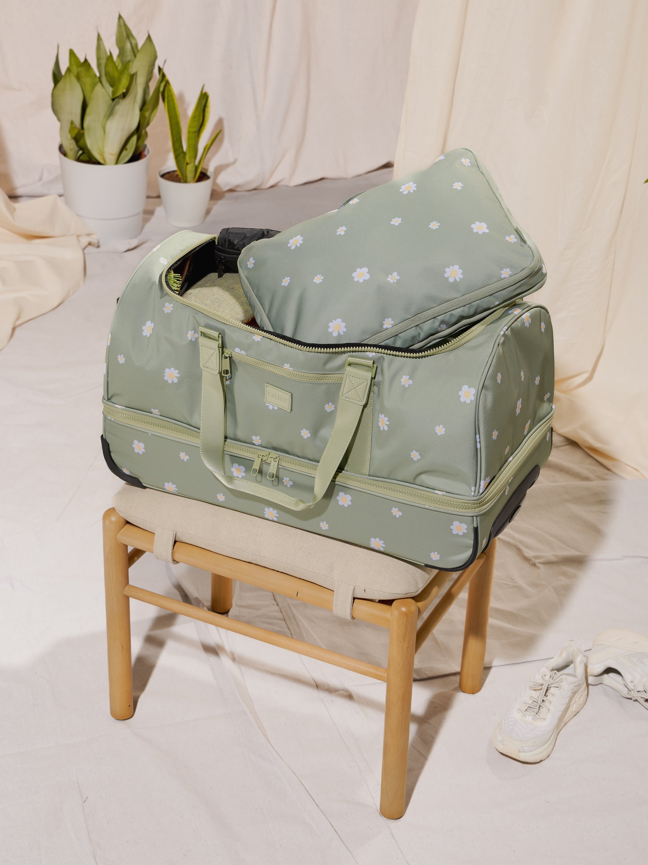 Packed CALPAK Stevyn Rolling Duffel bag with dual handles, wheels and shoe compartment in green floral daisy print