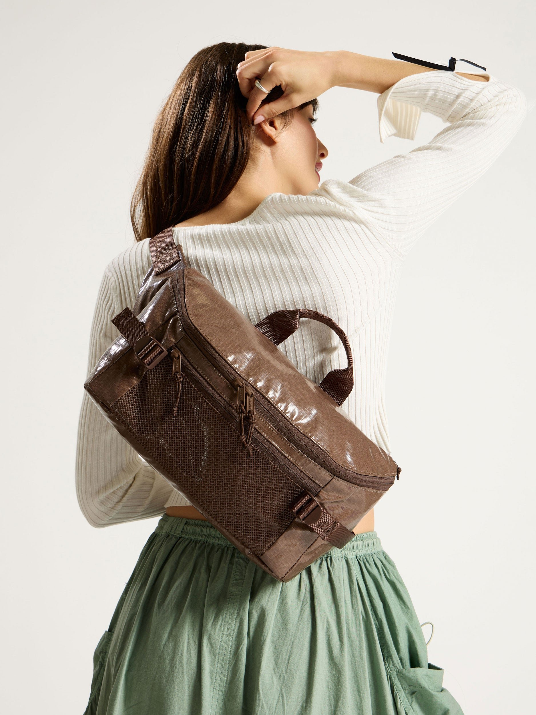 Model wearing CALPAK Terra Sling Bag in chocolate as crossbody bag