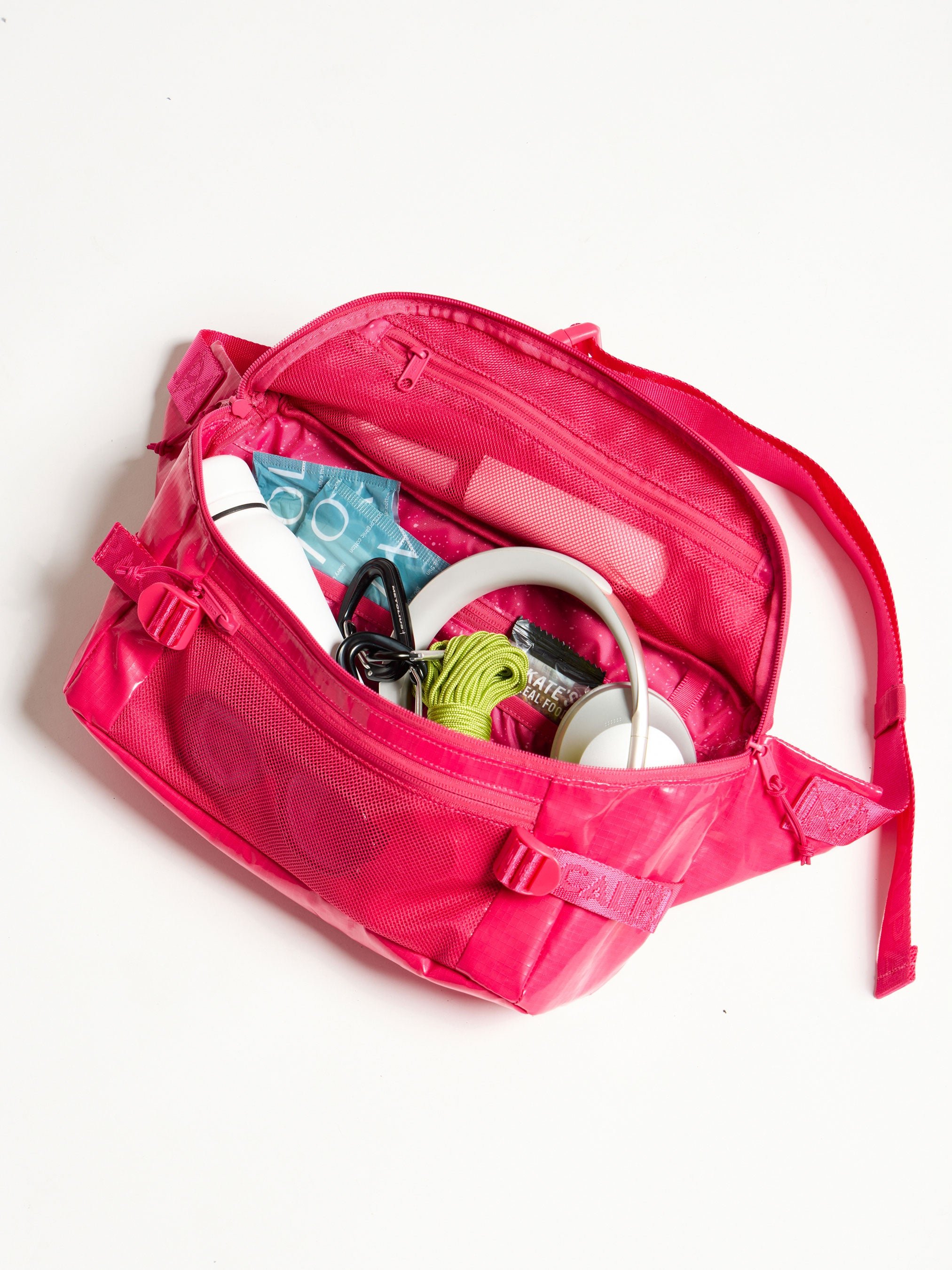 Close of shot of the interior of CALPAK Terra Sling Bag in pink dragonfruit with belongings inside