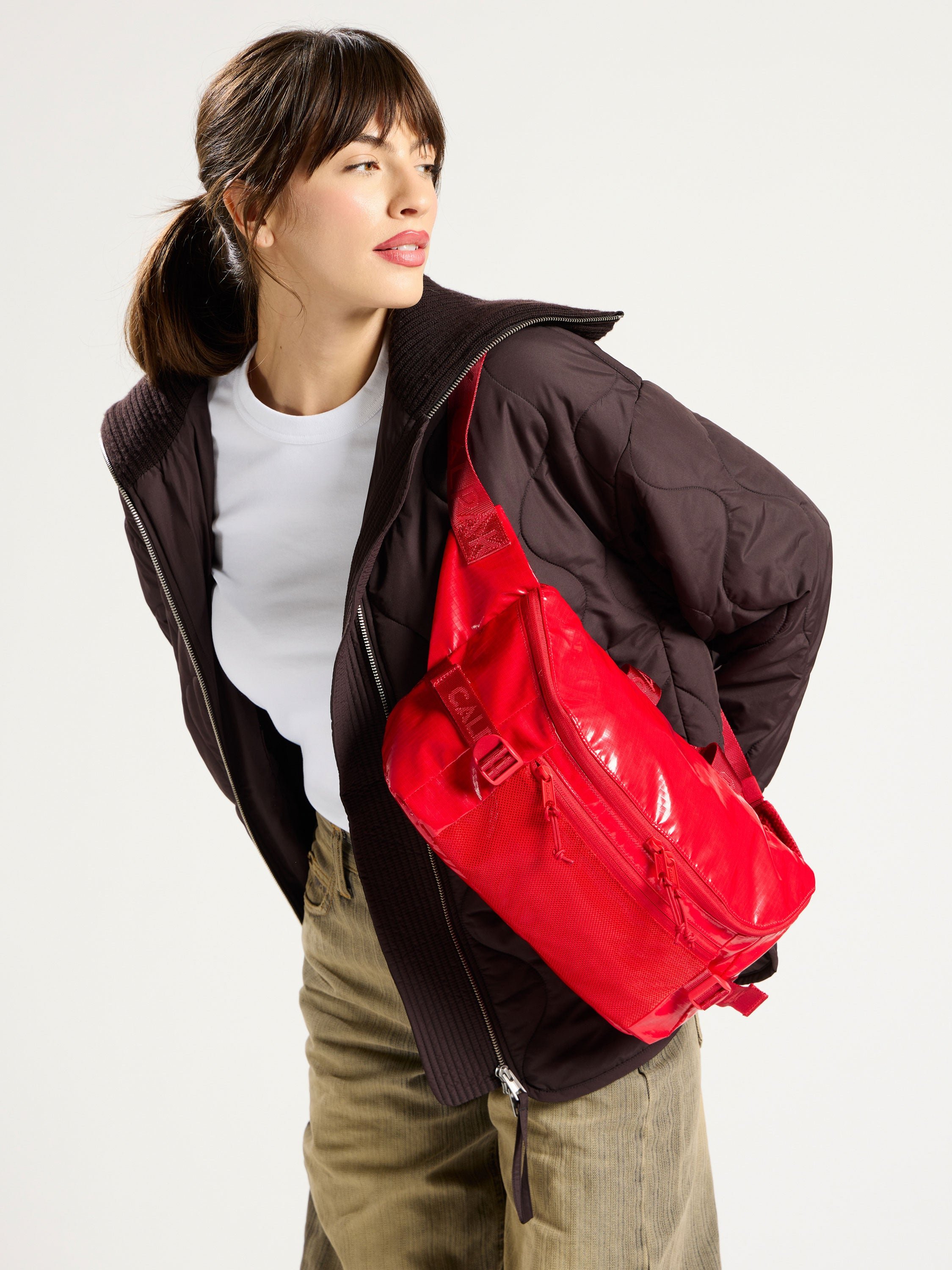 Model wearing CALPAK Terra Sling Bag over shoulder in flaming red