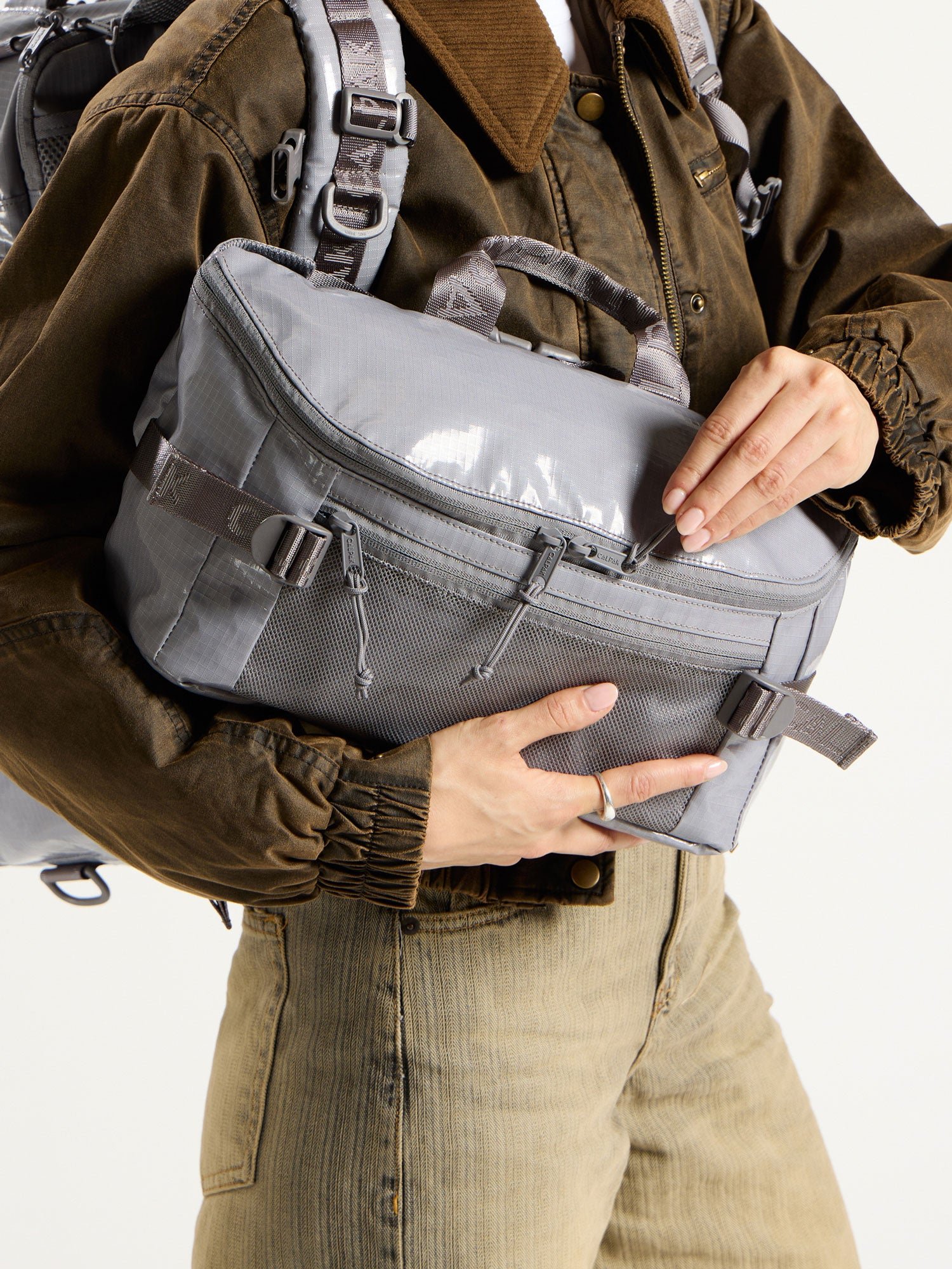 Model showing main zippered compartment of CALAPK Terra Sling Bag in gray
