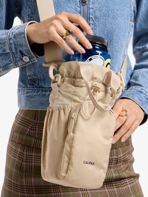 Model placing water bottle within CALPAK Water Bottle Holder in oatmeal; AWH2101-OATMEAL