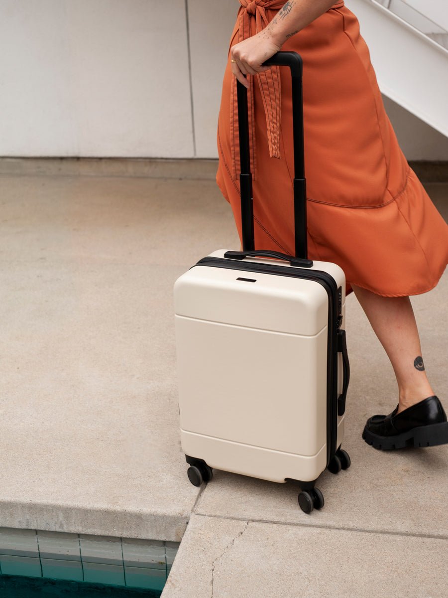 CALPAK Hue rolling carry-on suitcase in linen cream color