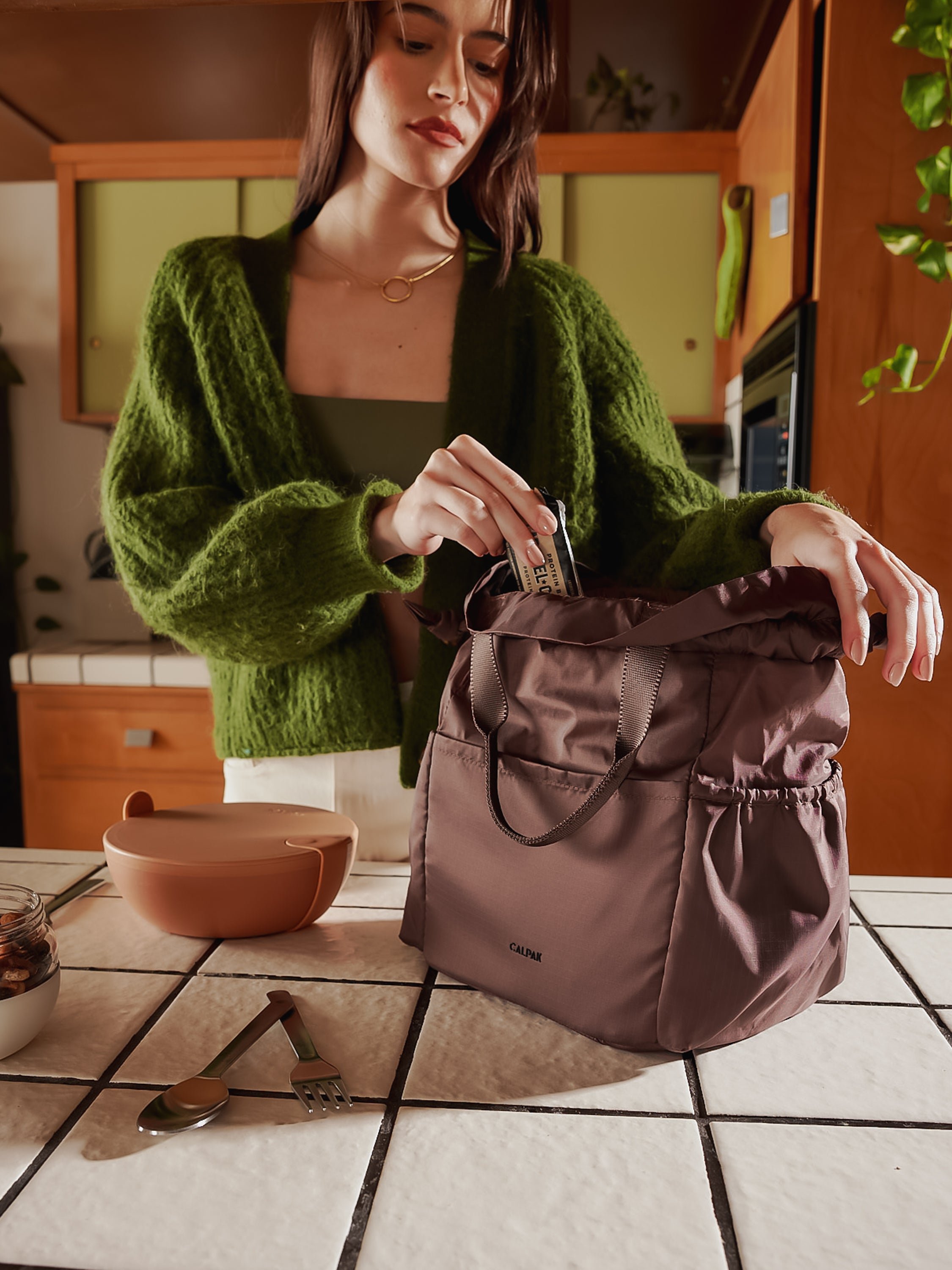 Model packing CALPAK Insulated Lunch Bag for women in walnut