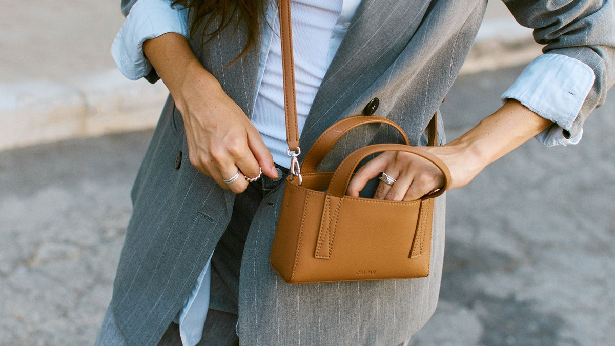 Woman in blazer wearing a taupe Haven Mini Crossbody Bag
