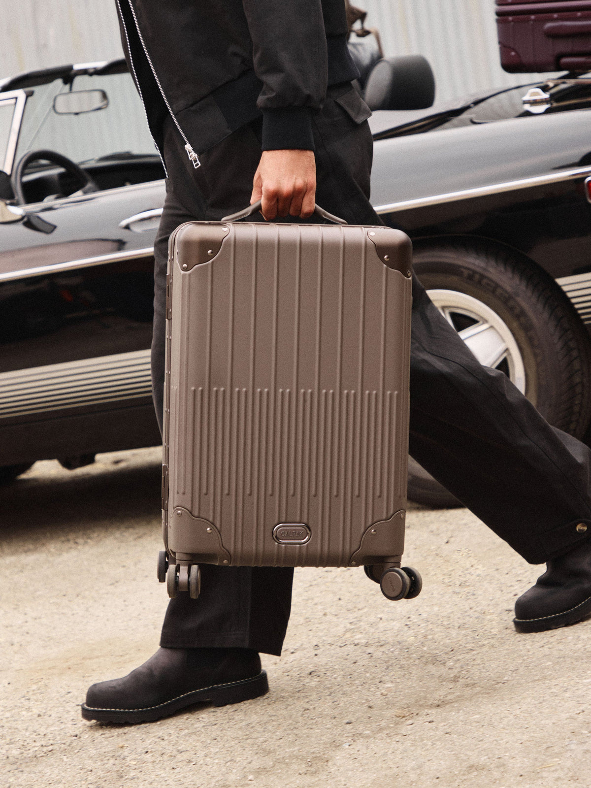 Man carrying the CALPAK Vault Carry-On Luggage by top handle