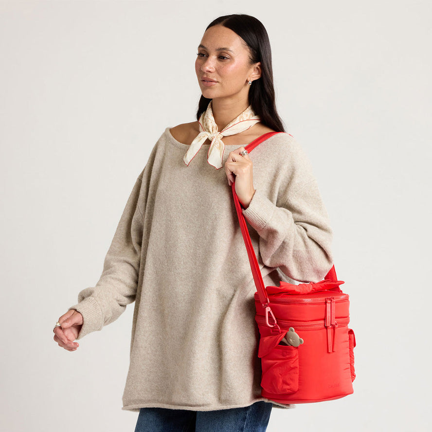 Woman carrying the CALPAK Baby Bottle Holder in red Tomato
