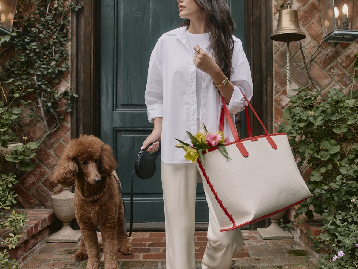 Woman with a poodle on leash while woman carries a CALPAK Colette Canvas 15" Laptop Tote