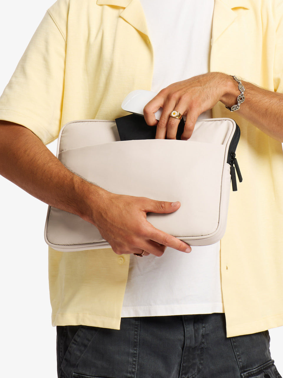 Model placing mouse and wallet into back pocket of CALPAK Luka 14" Padded Laptop Sleeve in oatmeal; ALL2401-OATMEAL