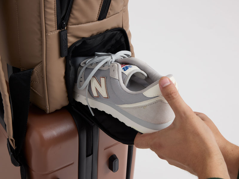 CALPAK Luka Duffel in  chocolate with shoe compartment being used by model to put in sneakers