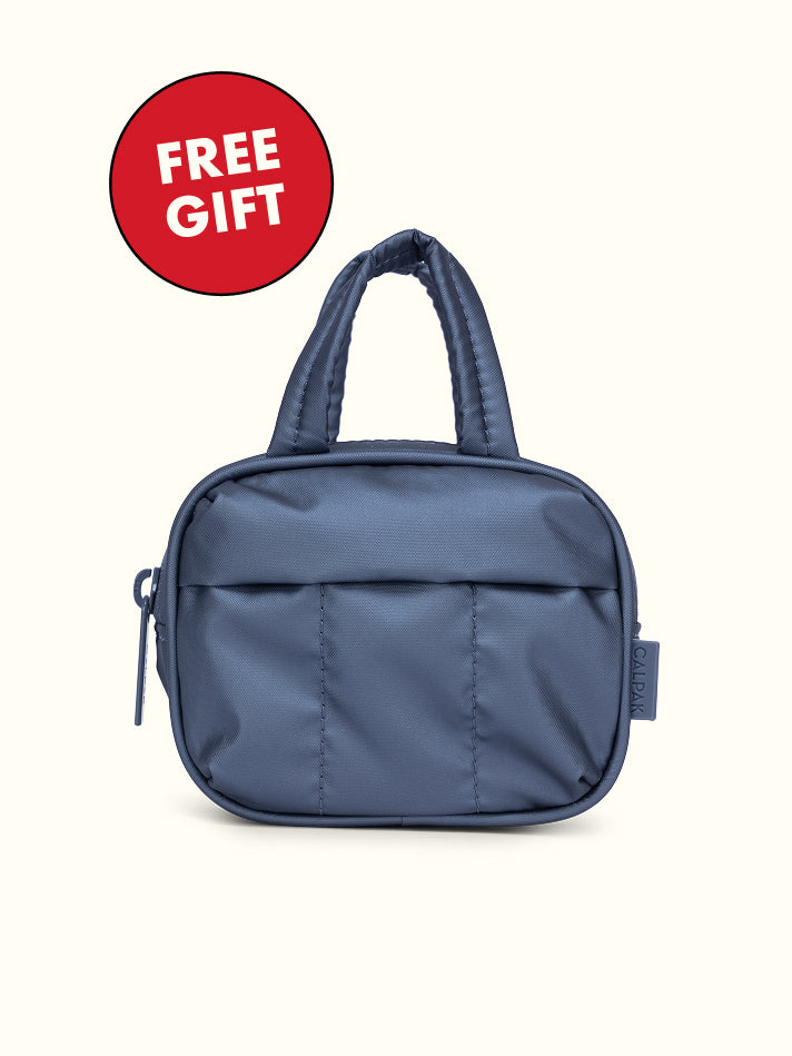 Indigo CALPAK Luka Duffel Zip Bag Charm with a free gift badge on a white background