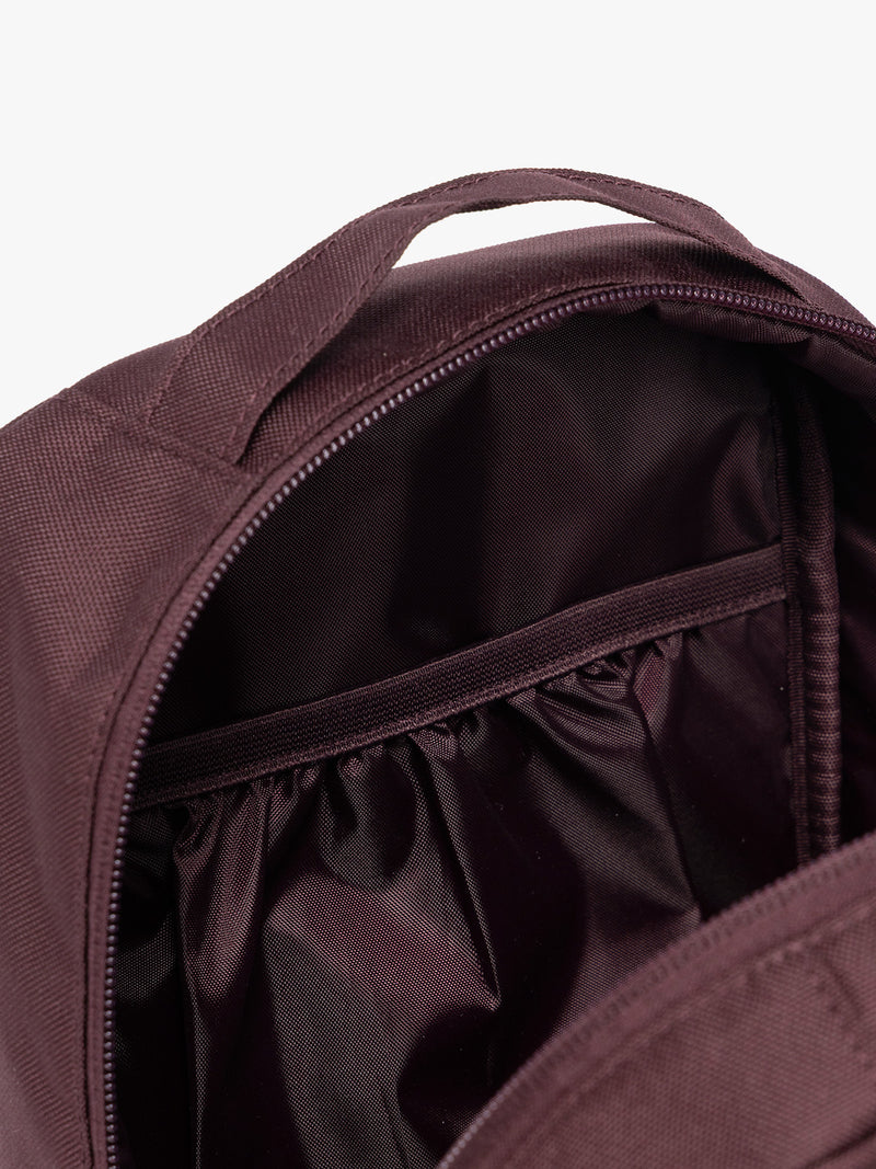Closeup of the inner compartments of Dark burgundy Dark Cherry color of the CALPAK Everything Cube organizer with a top handle, a front zippered pocket, and a textured mesh lower panel, shown against a plain white background