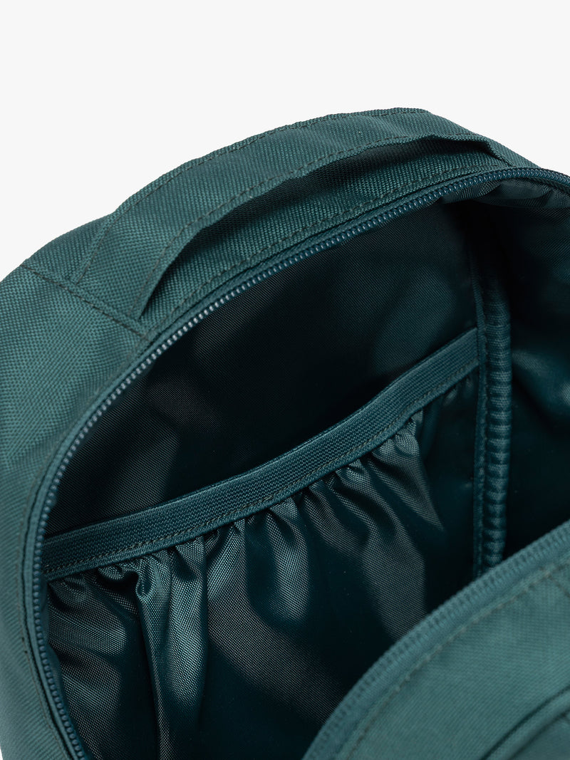 Close up of inside compartment of the dark teal green Kale CALPAK Everything Cube organizer with a top handle, a front zippered pocket, and a textured mesh lower panel, shown against a plain white background
