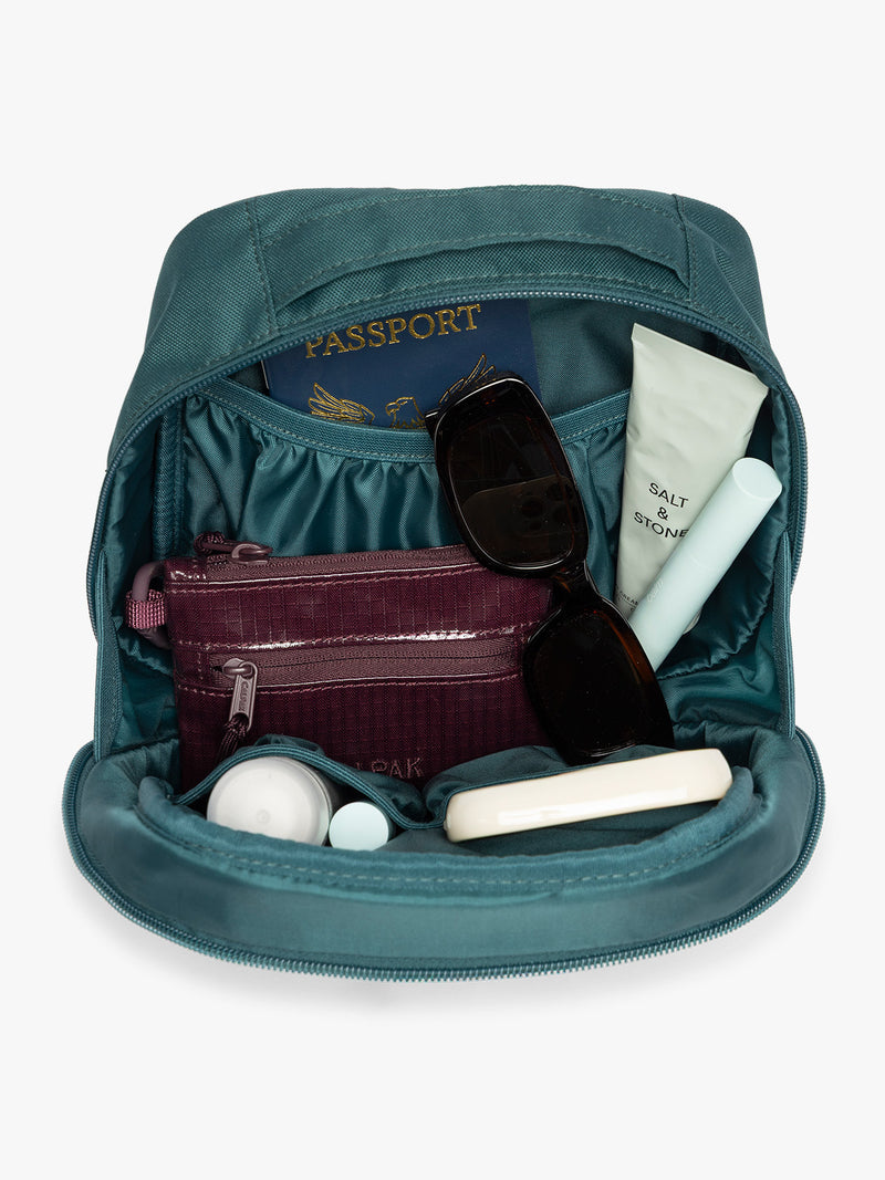 Inside of a dark teal green Kale CALPAK Everything Cube organizer with a top handle, a front zippered pocket, and a textured mesh lower panel, shown against a plain white background