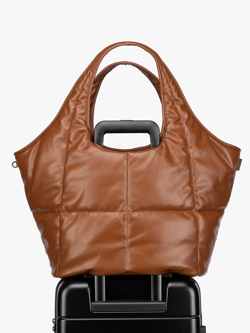 Luggage trolley sleeve feature of the Honey Brown quilted puffer CALPAK Luka Everything Tote Bag with a smooth finish and double shoulder straps, shown against a plain white background