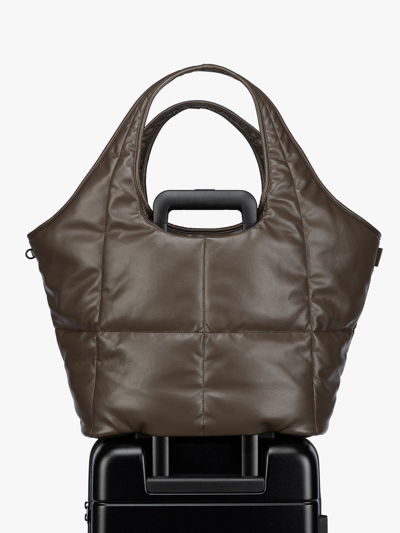Luggage trolley sleeve of the Mushroom brown quilted puffer CALPAK Luka Everything Tote Bag with a smooth finish and double shoulder straps, shown against a plain white background