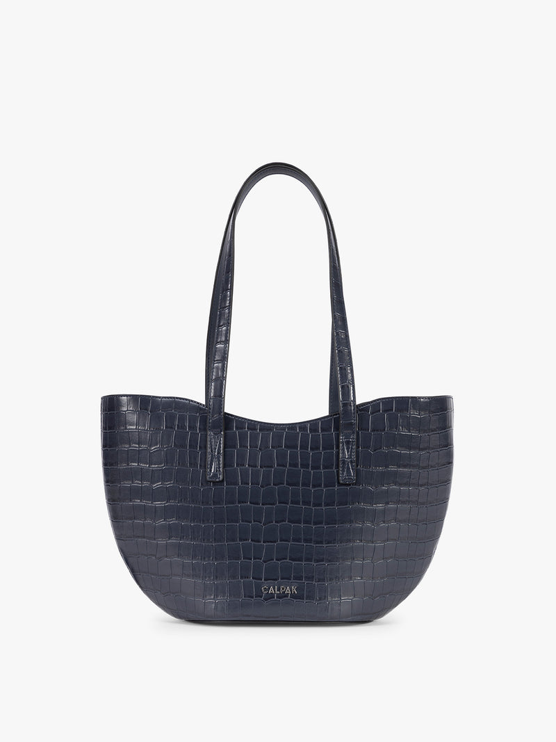 A navy blue crocodile-embossed CALPAK Haven Tulip tote bag with double shoulder straps against a plain white background