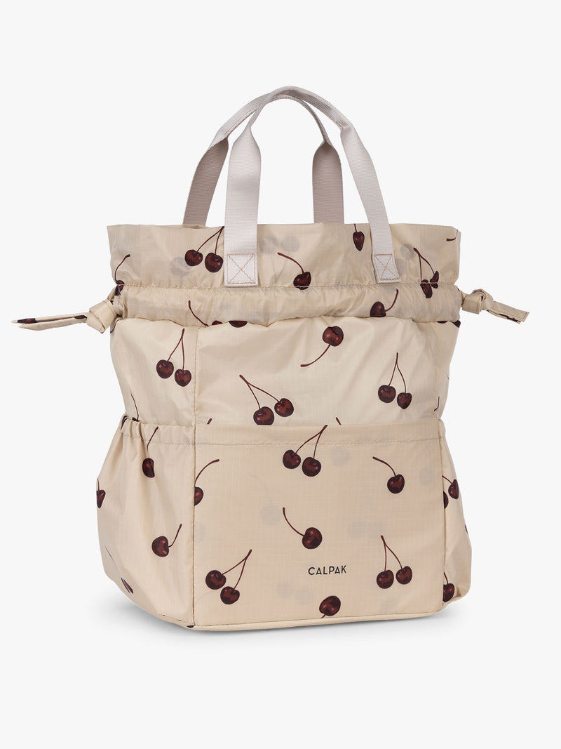 CALPAK Insulated Lunch Bag in Oatmeal Cherry in tan with cherry print with drawstring showing full height