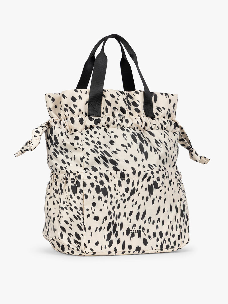 White and black Snow Leopard print CALPAK Insulated Lunch Bag with top handles, featuring an expandable function shown against a plain white background