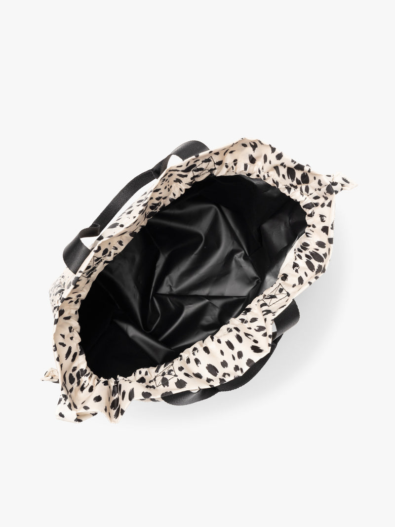 Opened white and black animal print Snow Leopard CALPAK Insulated Lunch Bag with top handles, featuring a white interior lining shown against a plain white background