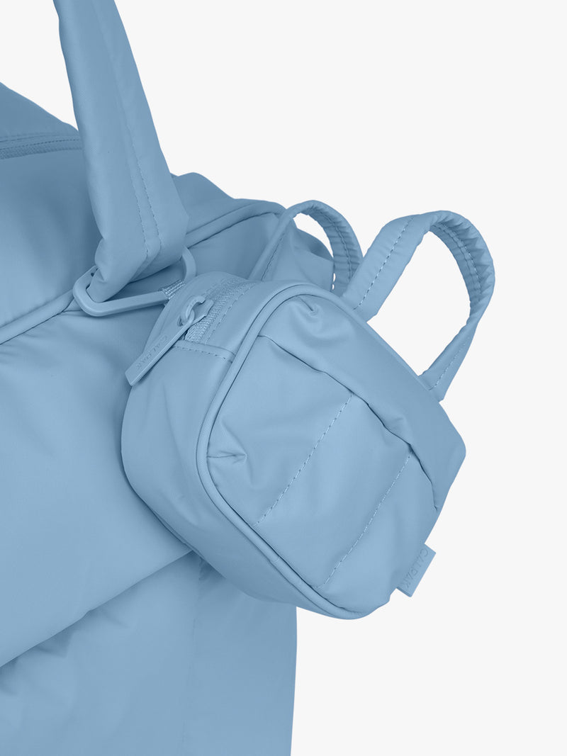 CALPAK Luka Duffel Zip Bag Charm in light blue French Blue clipped on a bag