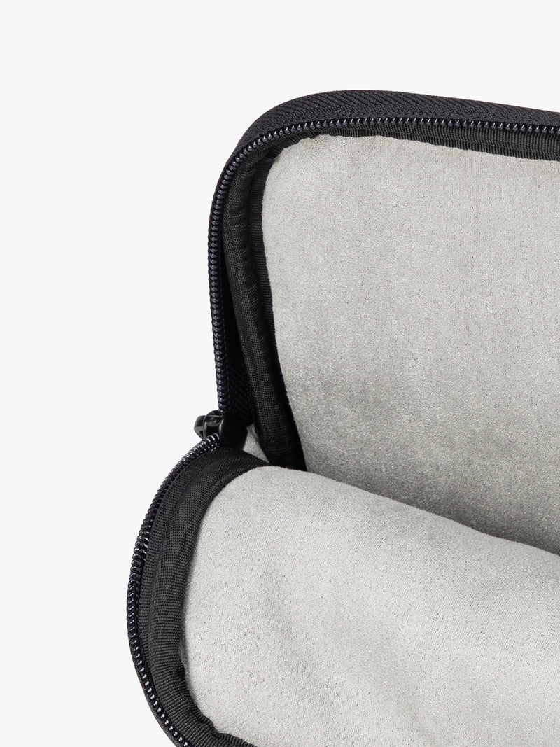 Interior of a black vegan leather CALPAK Luka 14in Laptop Sleeve with a zippered top and a front pocket, shown against a plain white background