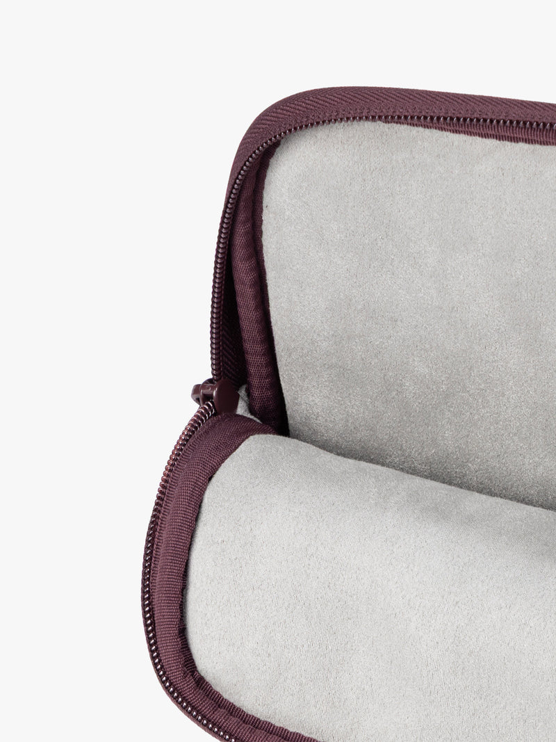 Opened interior of a deep burgundy Dark Cherry vegan leather CALPAK Luka 14in Laptop Sleeve with a zippered top and a front pocket, shown against a plain white background