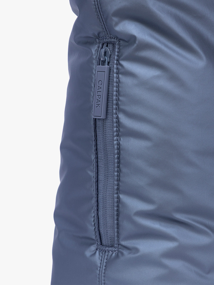 Side pocket with zipper of CALPAK Luka Expandable Tote in dark blue metallic material in Metallic Indigo; ALT2201-METALLIC-INDIGO