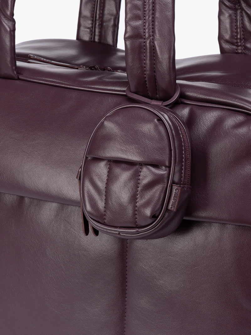 A close-up of dark burgundy Dark Cherry CALPAK Luka Backpack Zip Bag Charm leather backpack keychain featuring a matching bag shown on a plain white background