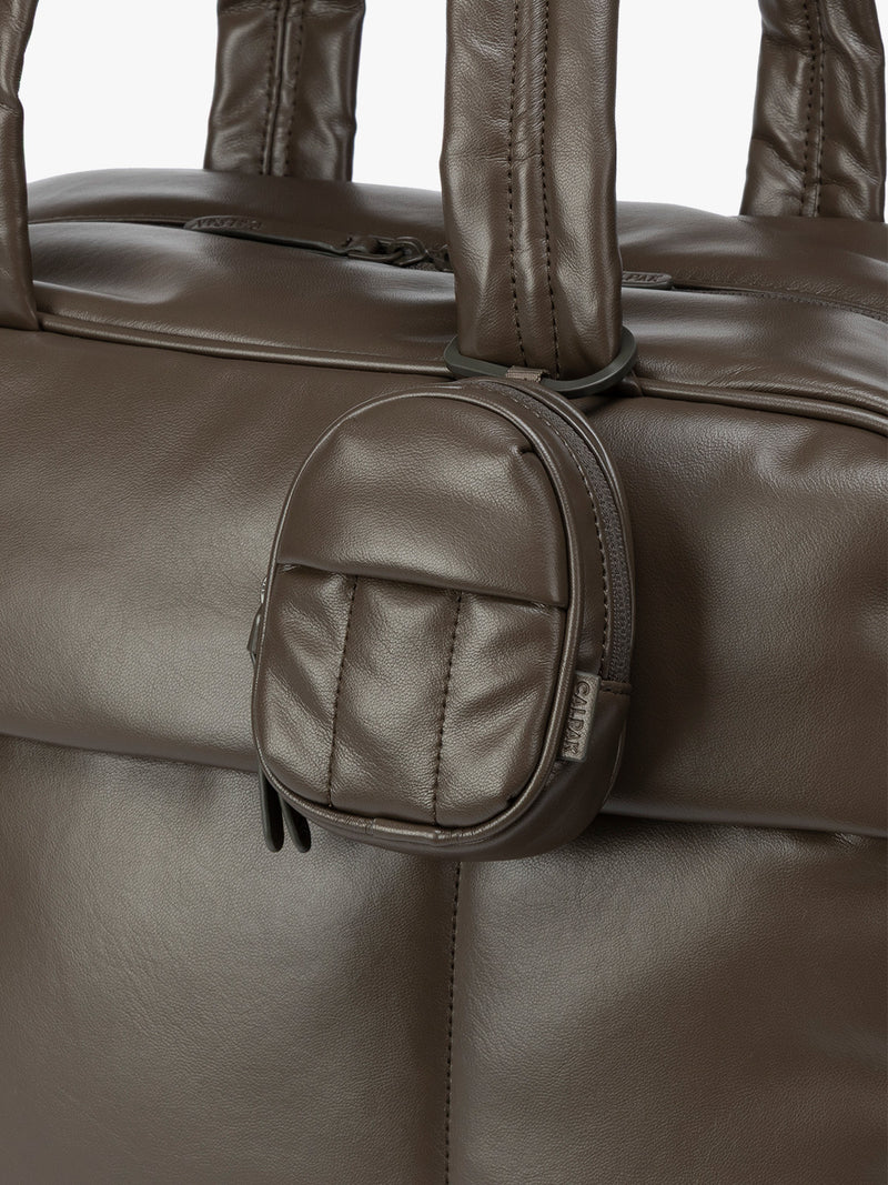 A close-up of dark brown Mushroom CALPAK Luka Backpack Zip Bag Charm leather backpack keychain featuring a matching bag shown on a plain white background