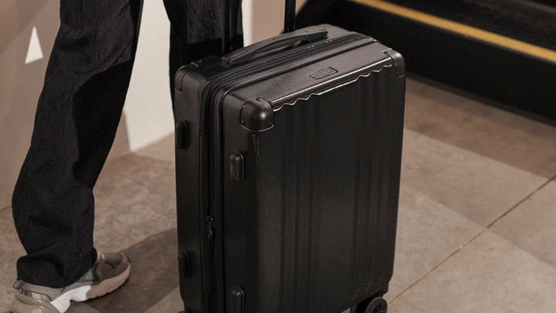 Ambeur Carry On Luggage in black being rolled by a model