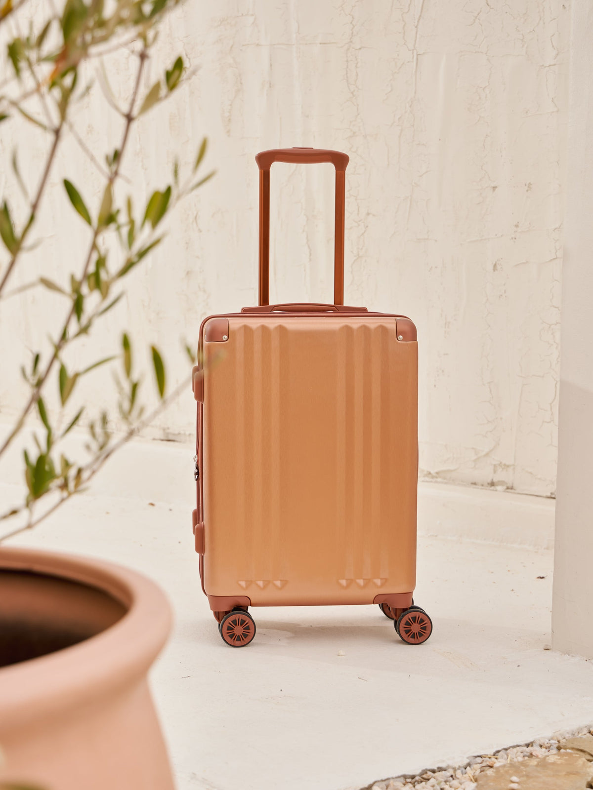 Front-facing image of CALPAK Ambeur carry-on luggage with 360 spinner wheels in copper; model LAM1020-COPPER, shown in an outdoor setting.