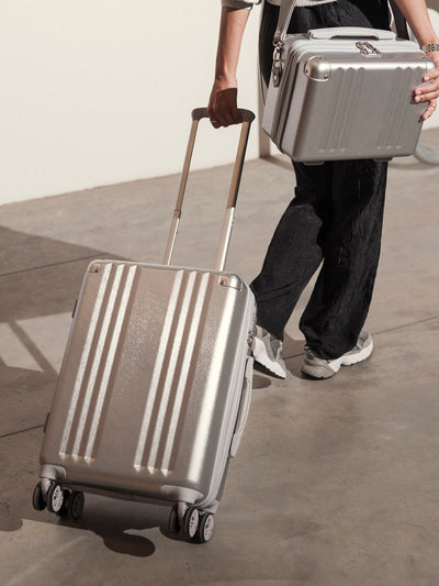 Studio product shot of front-facing lightweight silver CALPAK Ambeur 22-inch hardside rolling spinner carry-on luggage; model LAM1020-SILVER