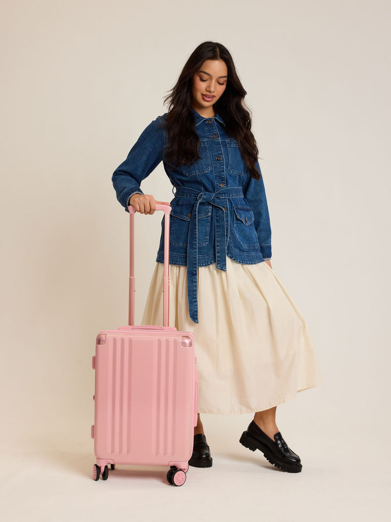Model with CALPAK Ambeur Carry-On Luggage in metallic pink Blossom with pink wheels