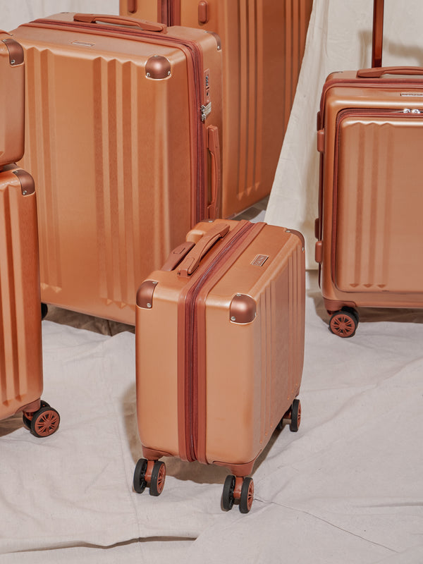 CALPAK Ambeur small carry-on luggage with wheels pictured with the Ambeur luggage collection in copper