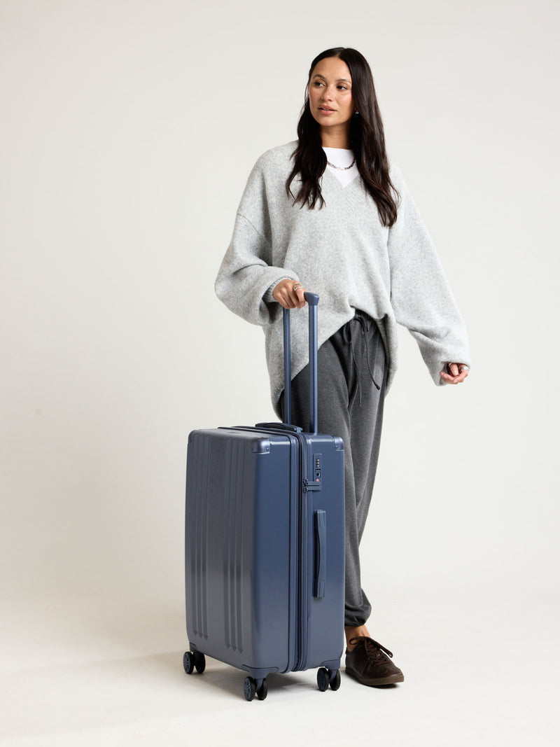 Model with CALPAK Ambeur Medium Luggage in dark blue metallic Indigo