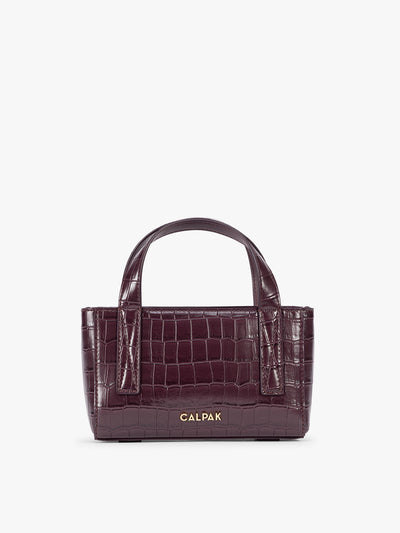 A CALPAK Haven Mini Crossbody Bag in deep red Dark Cherry crocodile-embossed with top handles on a plain white background; AMC2502-DARK-CHERRY-FAUX-CROC view 1