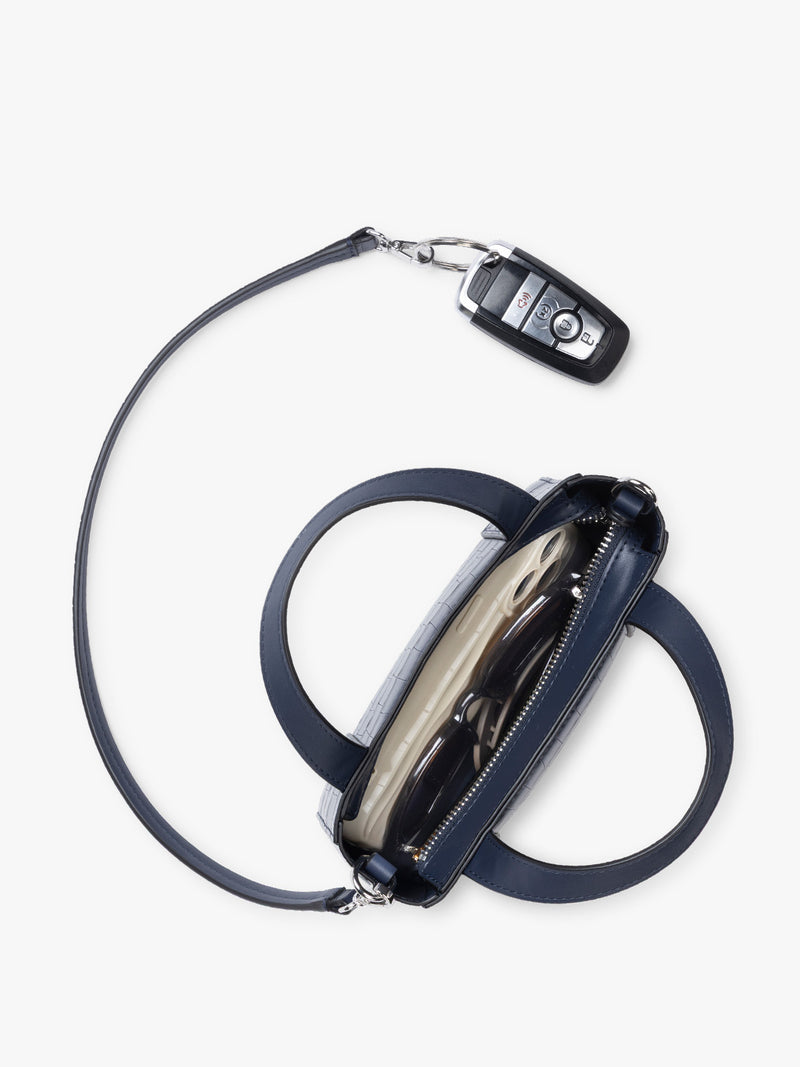 Top down view with key line and  CALPAK Haven Mini Crossbody Bag in Navy blue crocodile-embossed with top handles on a plain white background