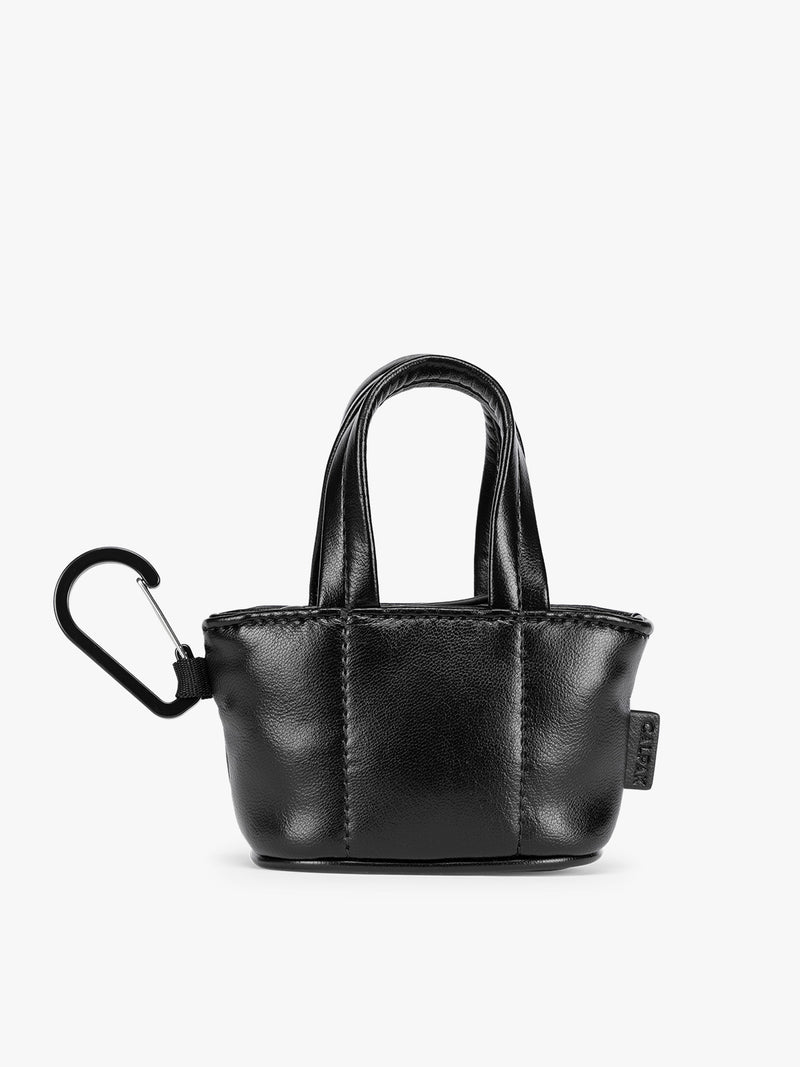 A small Black CALPAK Luka Tote Bag Charm with dual top handles and a black carabiner clip attached to the side, shown against a plain white background