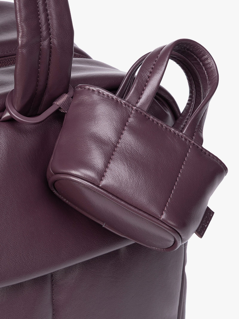 Closeup of A small deep burgundy Dark Cherry CALPAK Luka Tote Bag Charm with dual top handles and a black carabiner clip attached to the side, shown against a plain white background