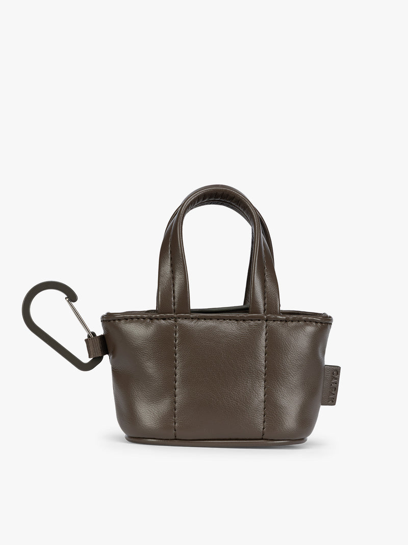 A small dark brown Mushroom CALPAK Luka Tote Bag Charm with dual top handles and a black carabiner clip attached to the side, shown against a plain white background