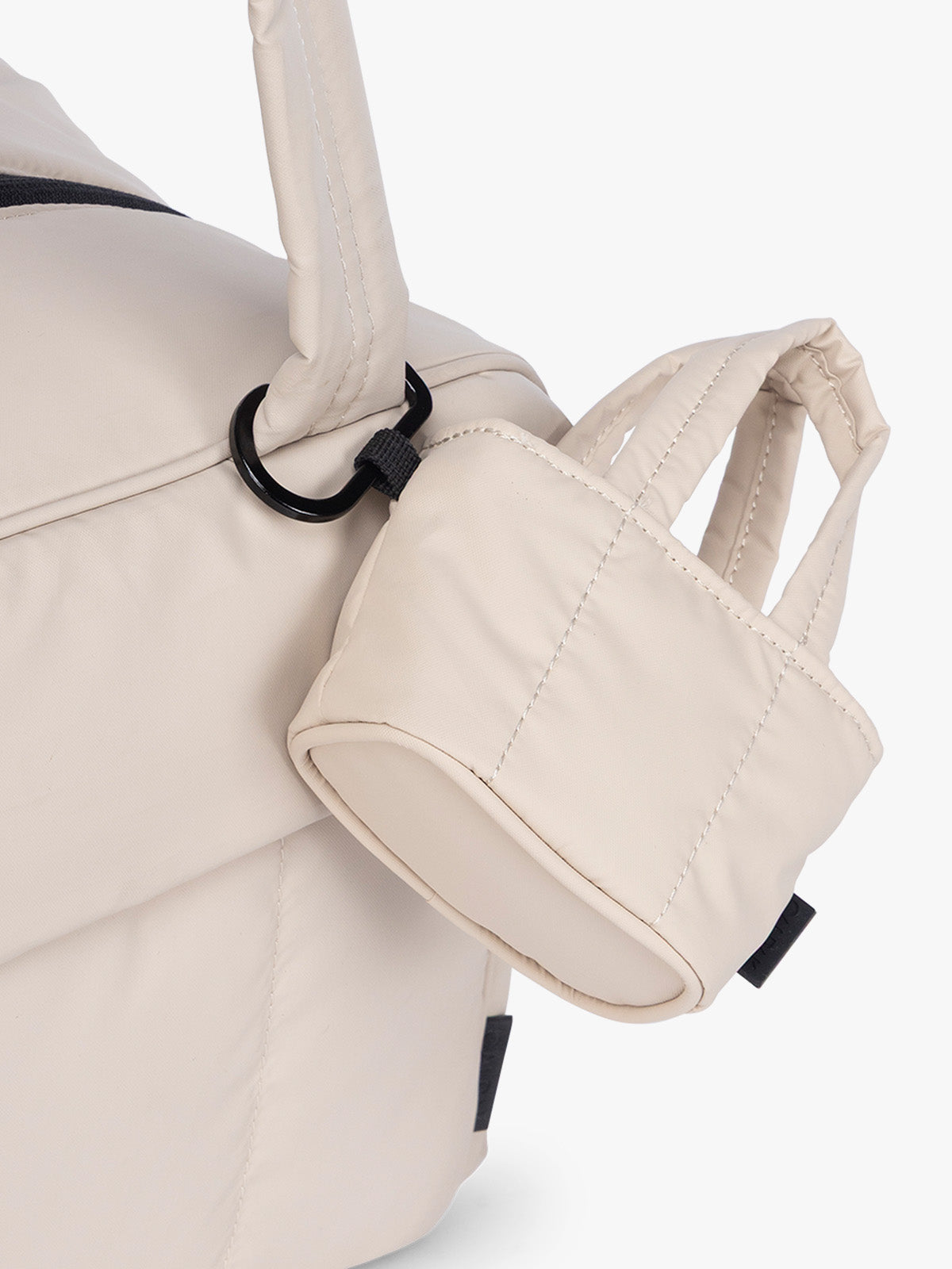 CALPAK Luka Tote Zip Bag Charm in off-white Oatmeal with carabiner attached to a bag; AMT2601-OATMEAL