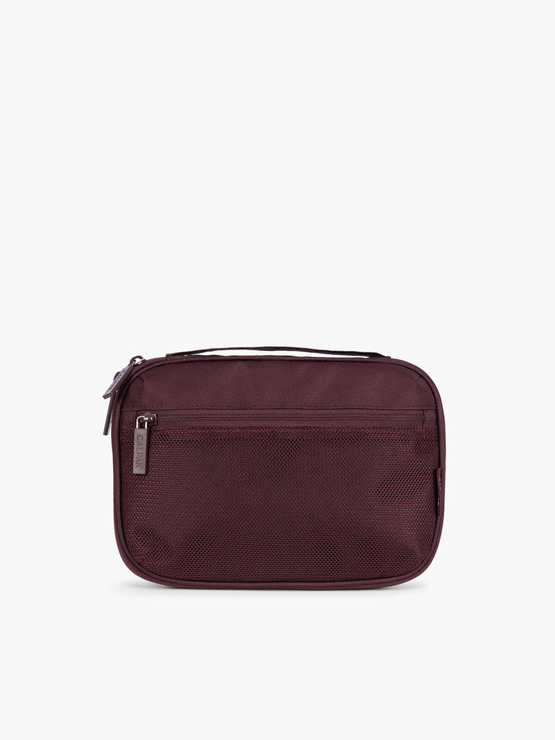 A dark burgundy CALPAK Tech Organizer pouch with a top zipper, front zippered pocket, and a small silver metal brand zipper, shown against a plain white background